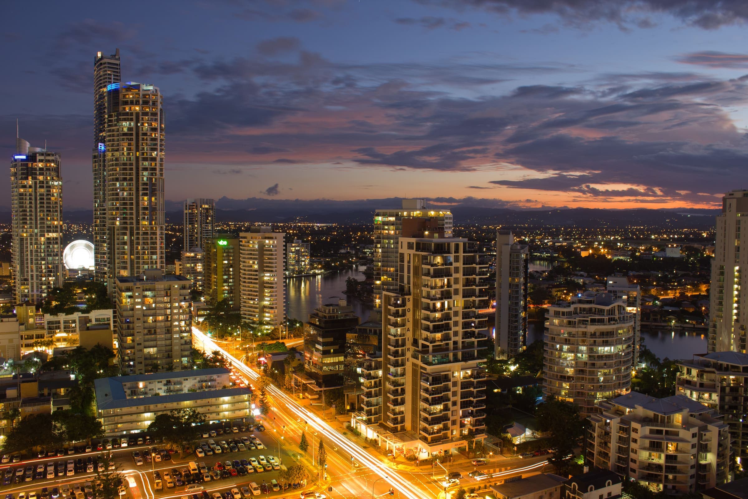 Gold Coast skyline and coastline at dusk, with Surfers Paradise high-rises lit against the evening sky